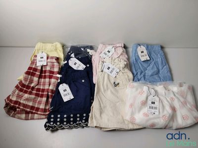 cinq paires de pantalons avec leurs étiquettes, posées sur une table