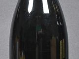 bottle of red wine with a red cap on a grey background