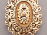 a close up of a gold broochle with pearls on it