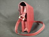 red leather handbag on a black background with a strap