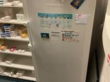 a refrigerator in the corner of a room with shelves of medicine