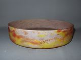 an orange and yellow bowl sitting on top of a white table