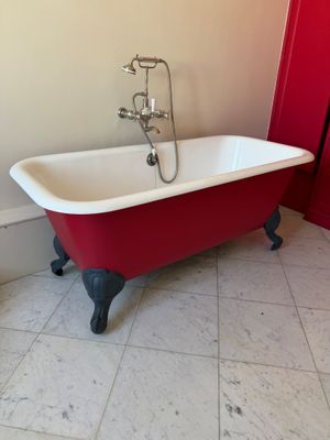 une baignoire rouge et blanche dans une salle de bains dont la porte est rouge
