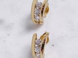 une paire de boucles d'oreilles en or et diamants posée sur une surface en marbre