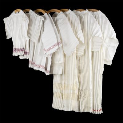several white shirts hanging on a clothes rack on a black background