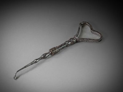 a silver spoon with a heart shaped handle on a gray surface