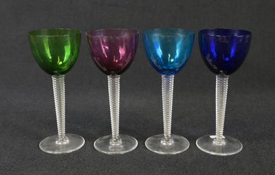 four wine glasses are lined up in a row on a table