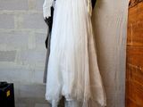 a wedding dress hanging on a clothes rack in a room