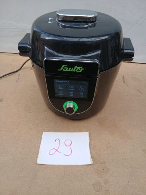 une photo d'un autocuiseur électrique noir posé sur une boîte en carton