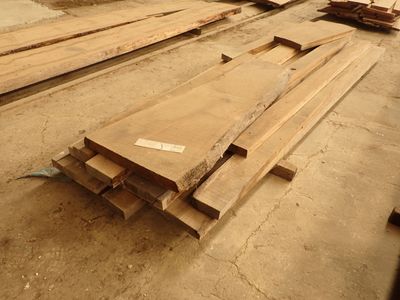 Plusieurs morceaux de bois sont empilés par terre dans un entrepôt