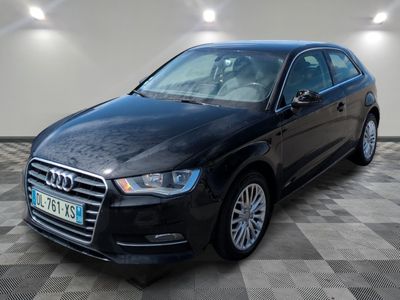 Une Audi noire est garée dans une grande pièce au sol en damier.