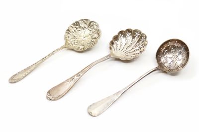 trois cuillères en argent ornées de feuilles, posées sur une surface blanche