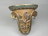 un vase doré et vert posé sur une surface blanche