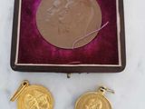 une image représentant une médaille d'or et une paire de boucles d'oreilles posées sur une surface en marbre
