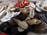 many pairs of shoes in a basket on a bed