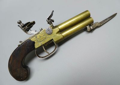 un vieux pistolet avec une poignée en bois sur une surface blanche