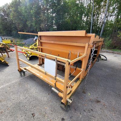 a yellow dump truck parked next to a pile of wood