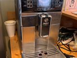 une machine à café posée sur une table en bois à côté d'un réfrigérateur