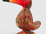 an orange and black toucan sitting on top of a wooden base