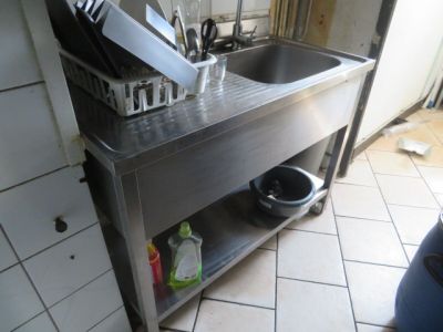 une cuisine équipée d'un évier en inox et d'une étagère en métal