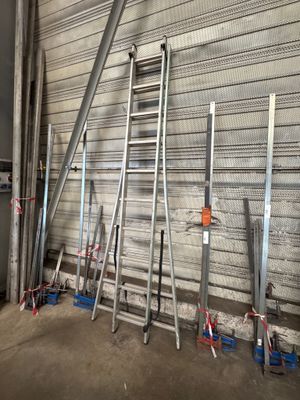 several ladders leaning against a wall in a warehouse