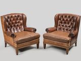 pair of leather armchairs with buttoned back and turned arms