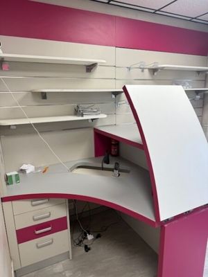 a pink and white desk in the corner of a room