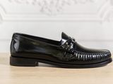 a close up of a black loafer on a wooden table