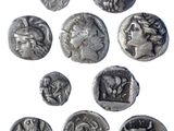 a close up of a group of ancient coins with faces on them