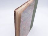 an open book with a green cover sitting on top of a white surface