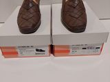 une paire de chaussures en cuir marron exposée dans une boîte blanche