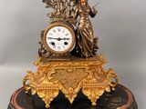 a statue of a woman holding a clock on top of a table