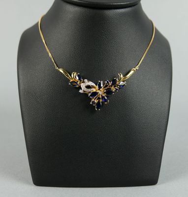 un collier en or orné de cristaux bleus et blancs sur un mannequin noir