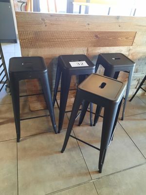quatre tabourets noirs placés devant un mur en bois
