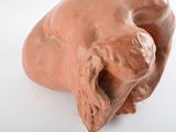 a clay sculpture of a dog laying down on a white surface