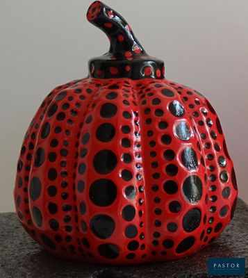 une citrouille à pois rouges et noirs posée sur une table