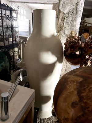 a white vase sitting next to a sink in a room
