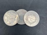 three silver coins sitting on top of each other on a black surface