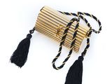 un sac à main noir et doré orné de pompons, sur fond blanc