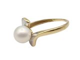a white pearl and gold ring on a white background