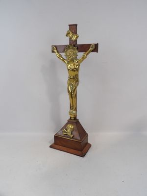 crucifix en or posé sur un socle en bois, sur fond blanc