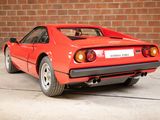 the rear end of a red sports car parked in front of a brick wall
