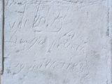 une vieille plaque en pierre portant une inscription, devant un mur de briques