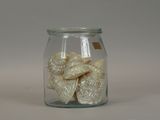 a glass jar filled with white candies on a white surface