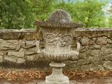 un vase en pierre posé sur un mur de pierre, près d'un mur de pierre
