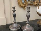 deux vases en argent posés sur une table à côté d'un miroir