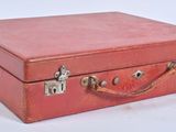 a small red suitcase with a handle on a white surface
