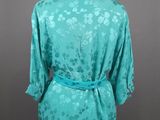 a woman ' s turquoise blouse with a floral pattern on it