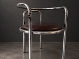une chaise avec une assise en cuir marron dans une pièce sombre