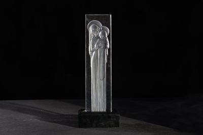 a clear glass sculpture of an angel on a black background
